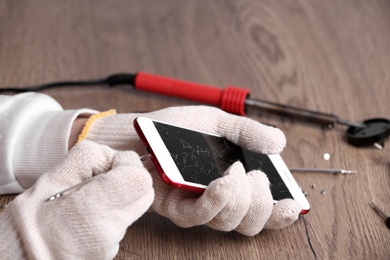 Photo of Technician fixing mobile phone at table, closeup. Device repair service