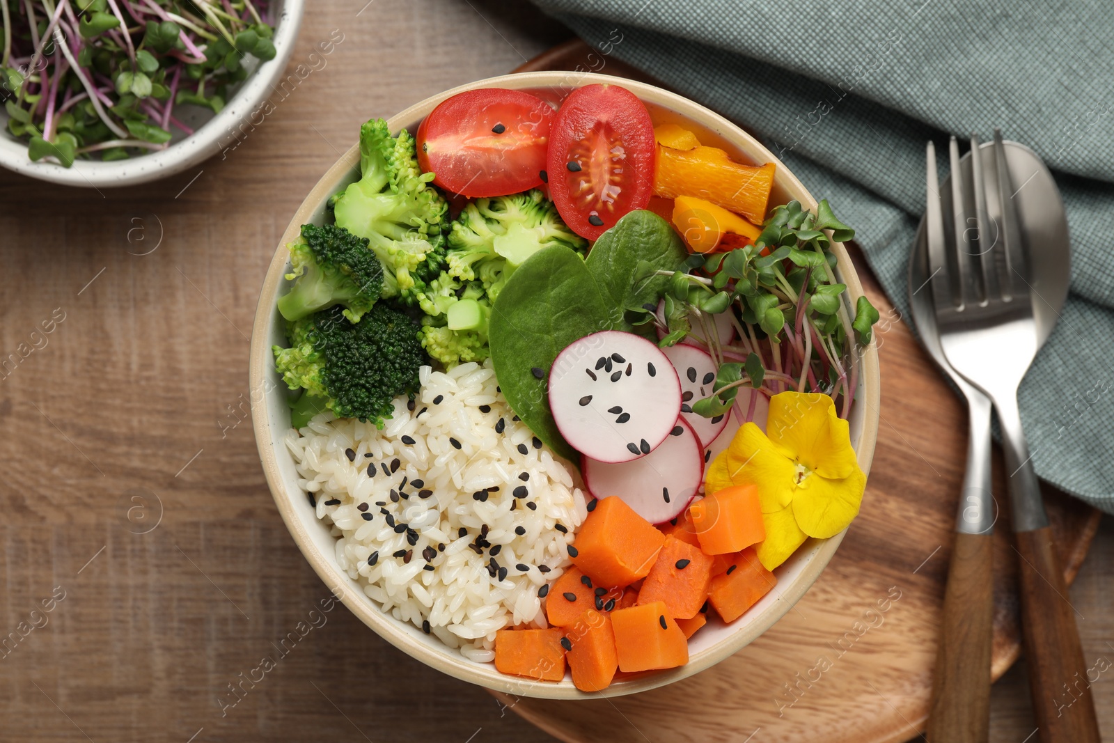 Photo of Bowl with many different vegetables and rice on wooden table, flat lay. Vegan diet