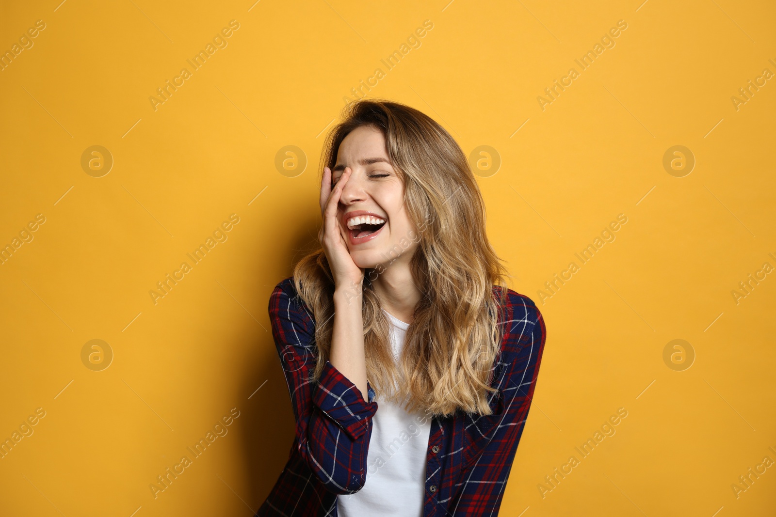 Photo of Cheerful young woman laughing on yellow background