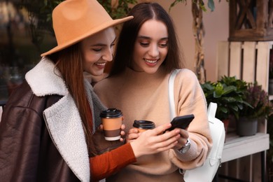 Happy friends with smartphone and paper cups outdoors