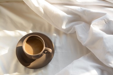 Photo of Aromatic morning coffee on bed, above view. Space for text