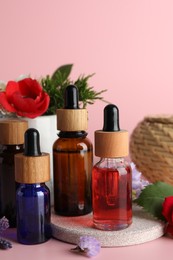 Photo of Aromatherapy. Different essential oils and flowers on pink background