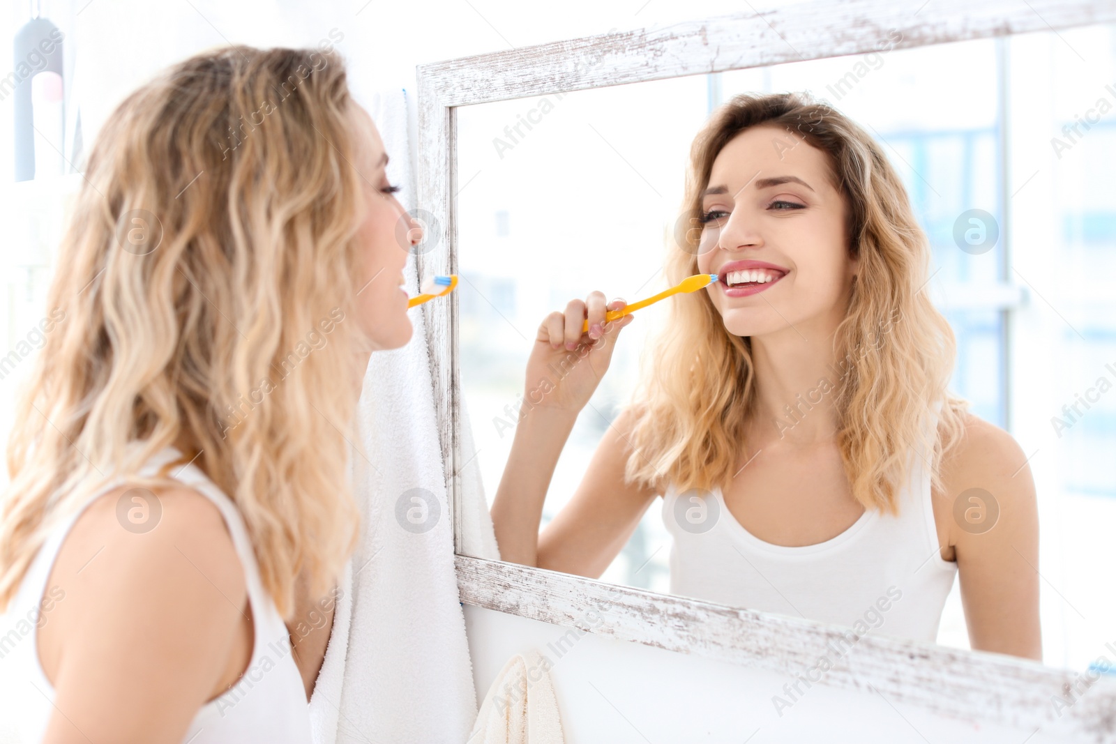 Photo of Young woman brushing her teeth in bathroom