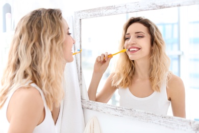 Young woman brushing her teeth in bathroom