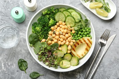 Healthy meal. Tasty vegetables and chickpeas in bowl on grey table, flat lay