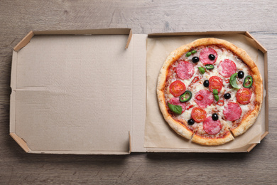 Photo of Delicious pizza Diablo in cardboard box on wooden background, top view