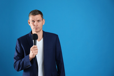 Photo of Male journalist with microphone on blue background. Space for text