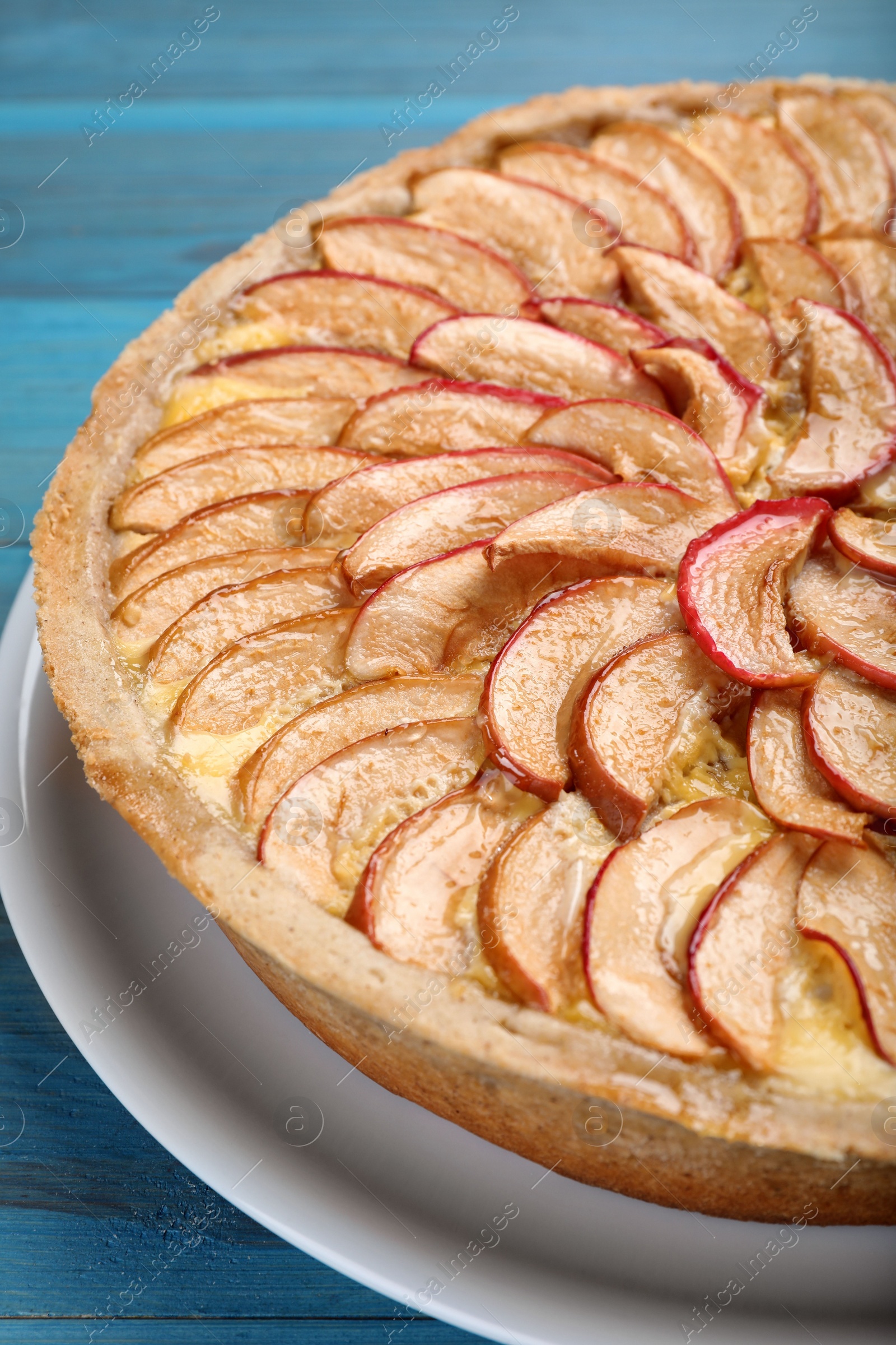 Photo of Tasty apple pie on light blue wooden table, closeup