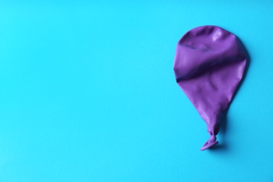 Purple deflated balloon on color background, top view with space for text