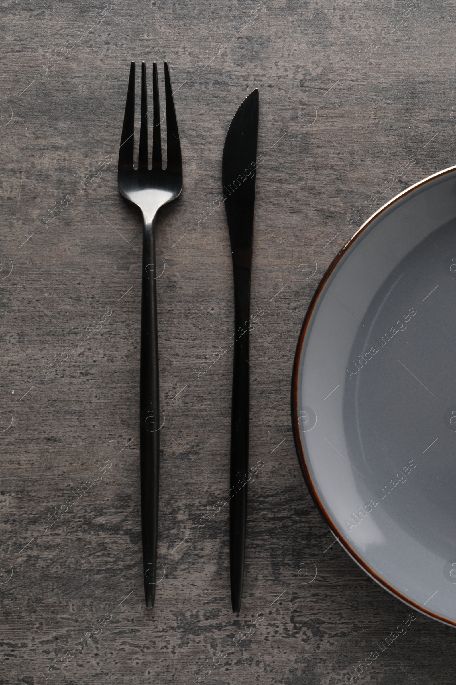 Photo of Stylish cutlery and plate on grey table, top view