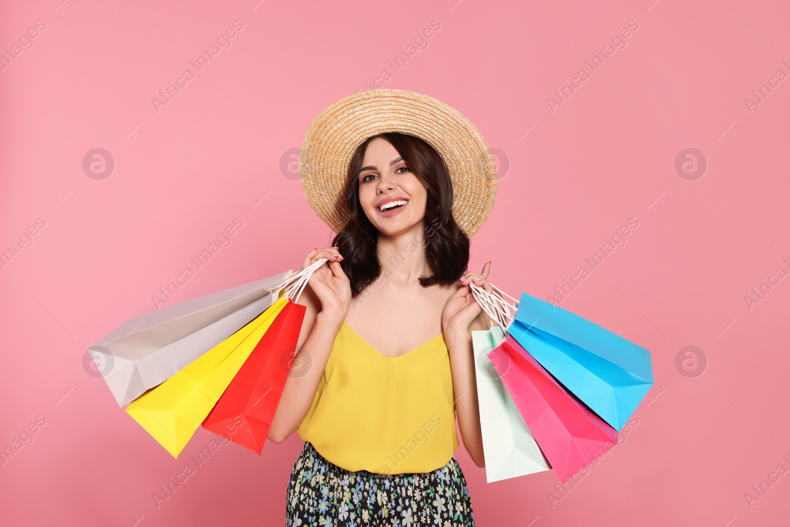 Photo of Beautiful young woman with paper shopping bags on pink background