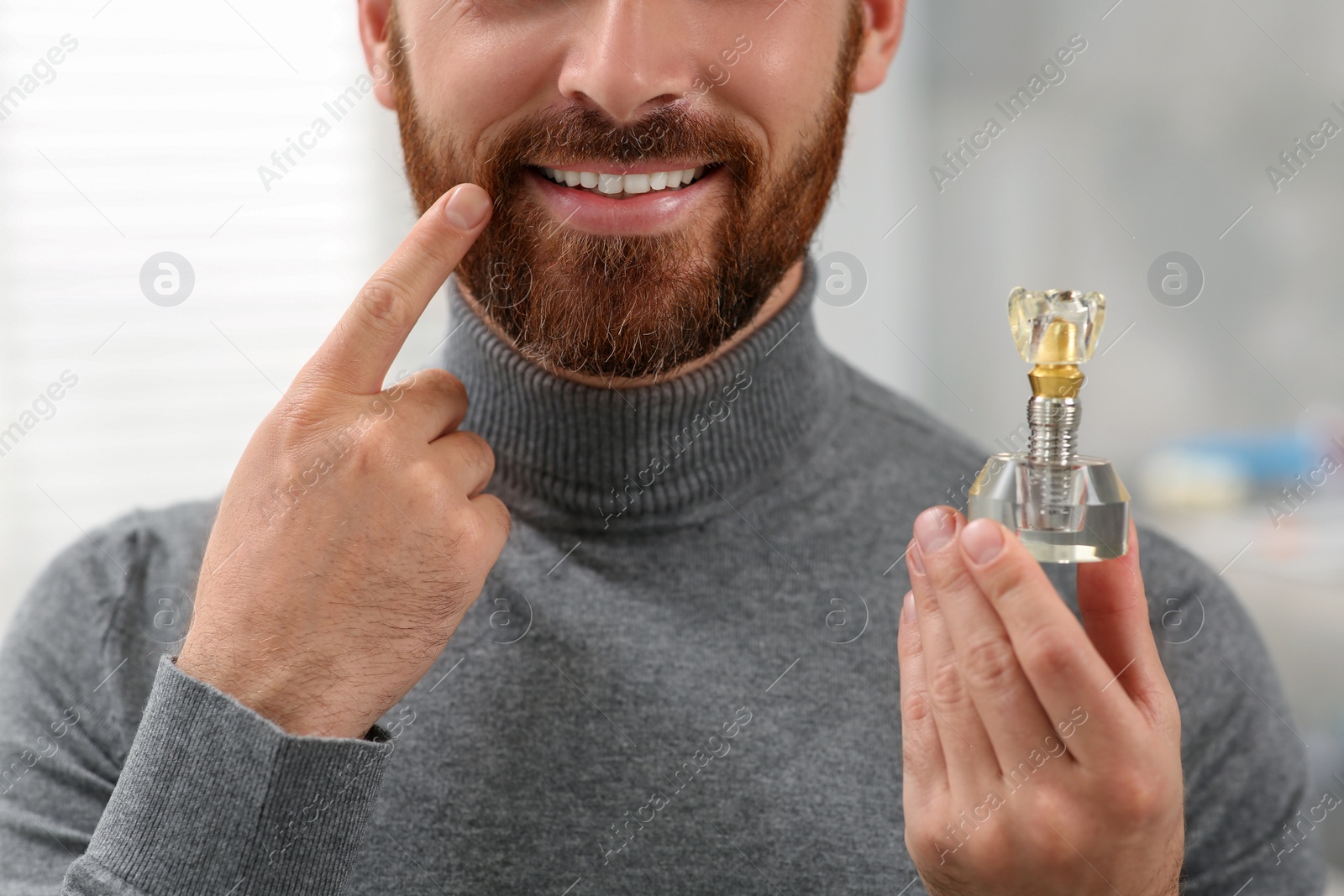 Photo of Man holding educational model of dental implant on blurred background, closeup