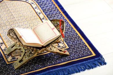 Photo of Rehal with open Quran and Misbaha on Muslim prayer rug, space for text
