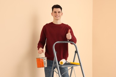 Young handsome man with paint can near metal stepladder indoors. Room renovation