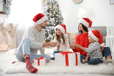 Photo of Happy family with children and Christmas gifts on floor at home