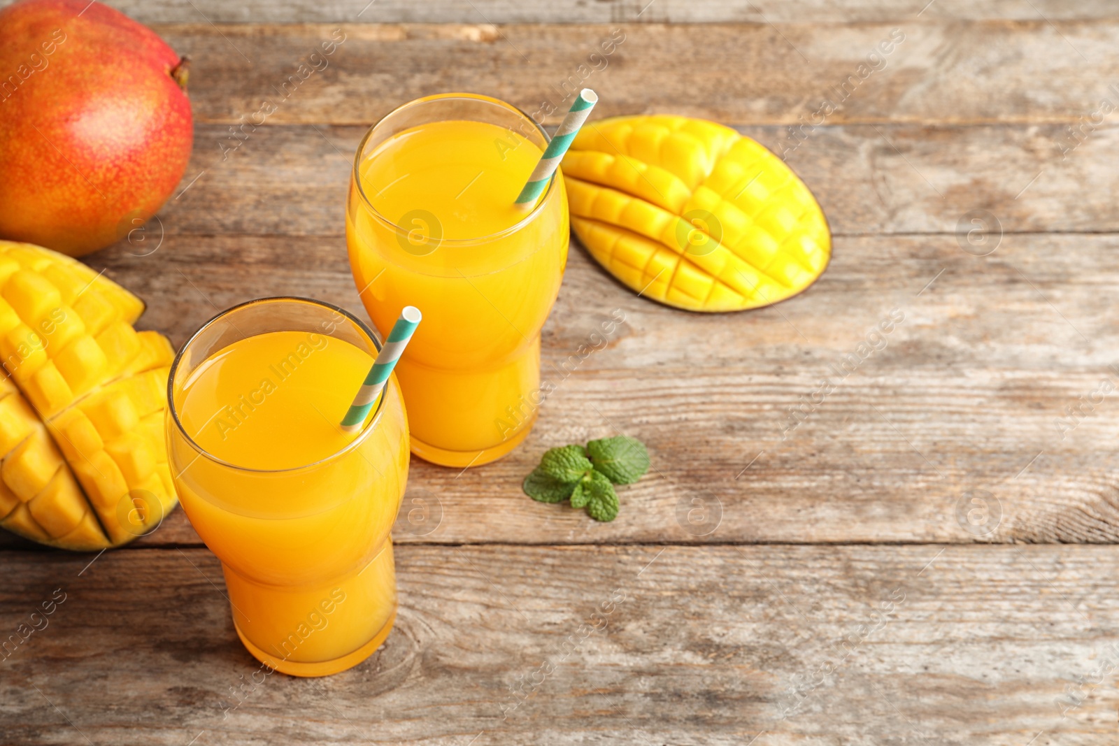 Photo of Fresh tropical mango juice, fruits and space for text on wooden table