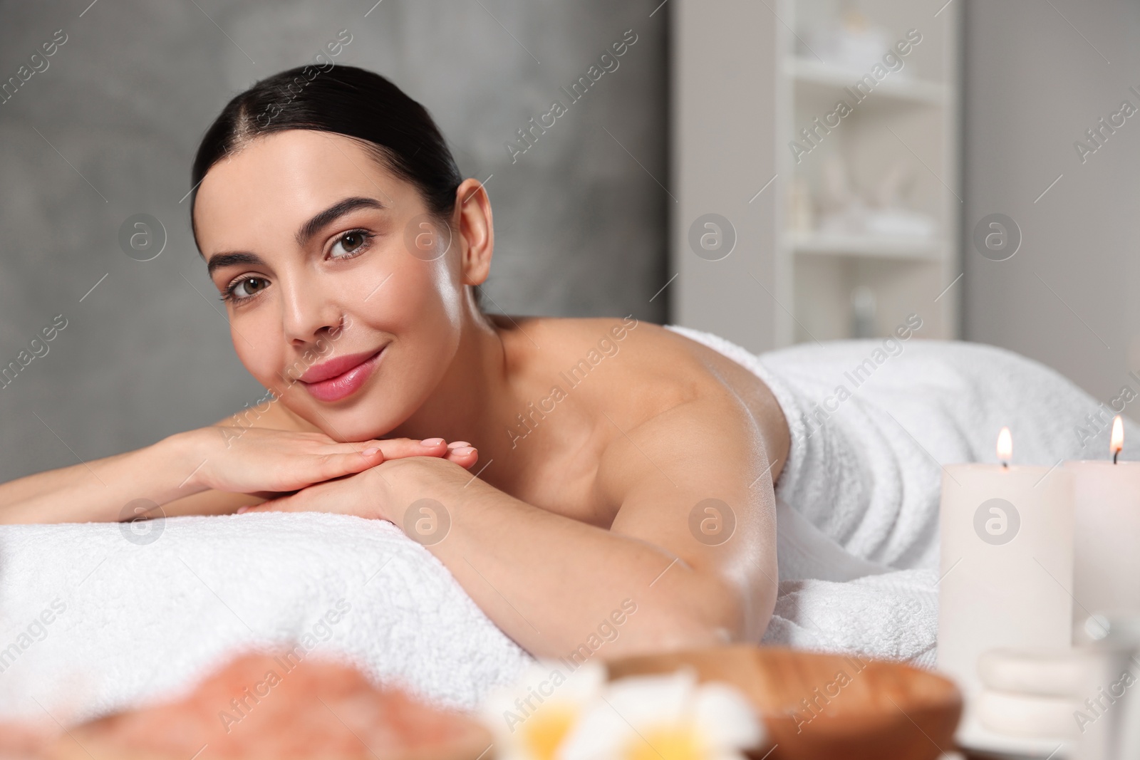 Photo of Beautiful happy woman relaxing on massage table in spa salon