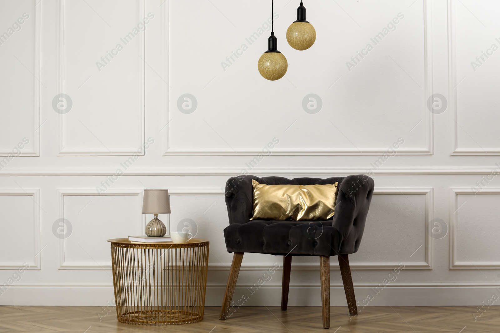 Photo of Stylish armchair with cushion and table near white wall indoors. Interior design