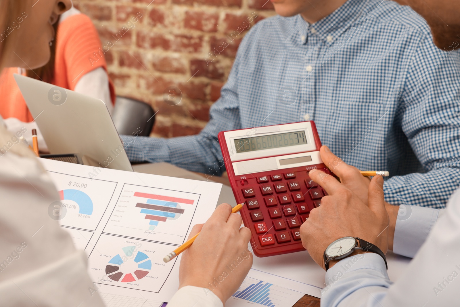 Photo of Team of employees working together at table in office, closeup