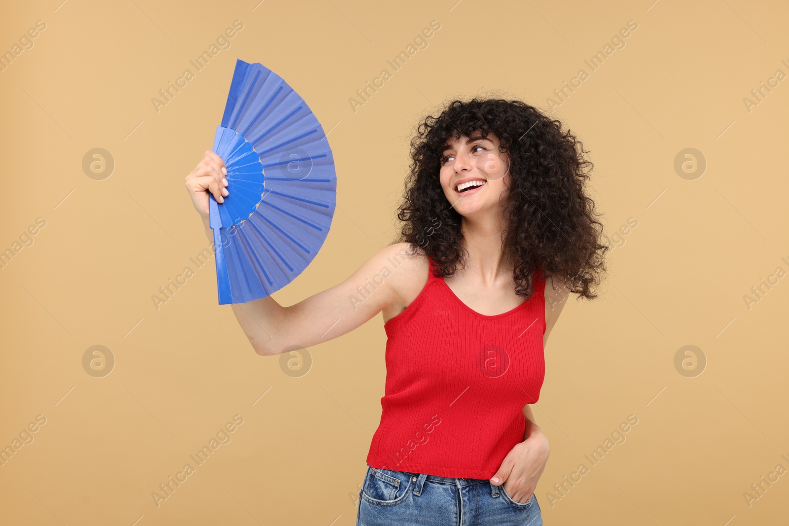 Photo of Happy woman holding hand fan on beige background