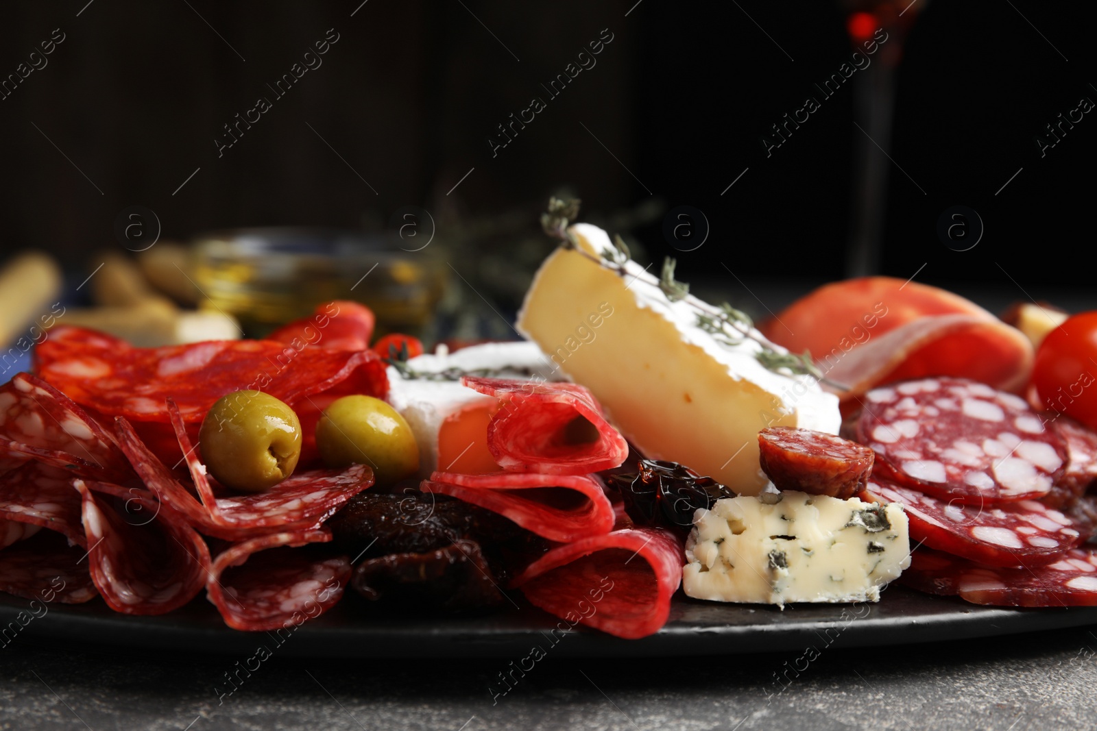 Photo of Tasty salami and other delicacies served on grey table, closeup