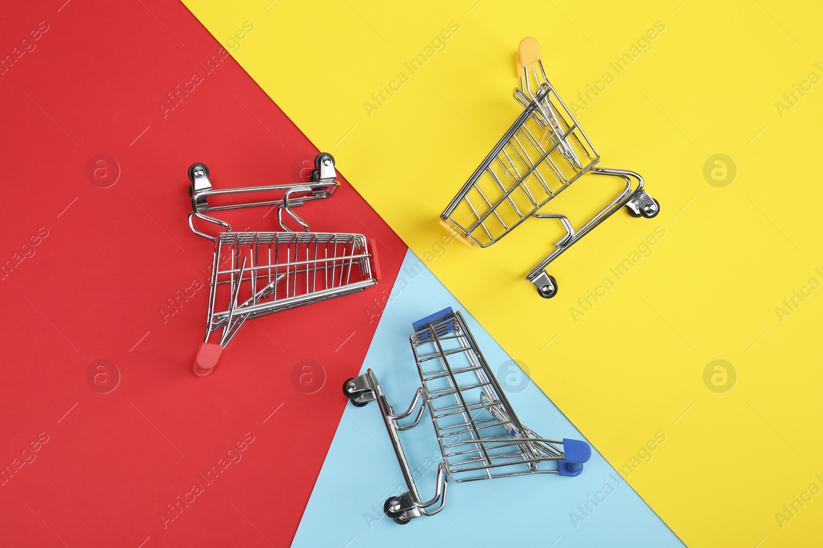 Photo of Flat lay composition with empty shopping trolleys on color background