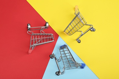 Photo of Flat lay composition with empty shopping trolleys on color background