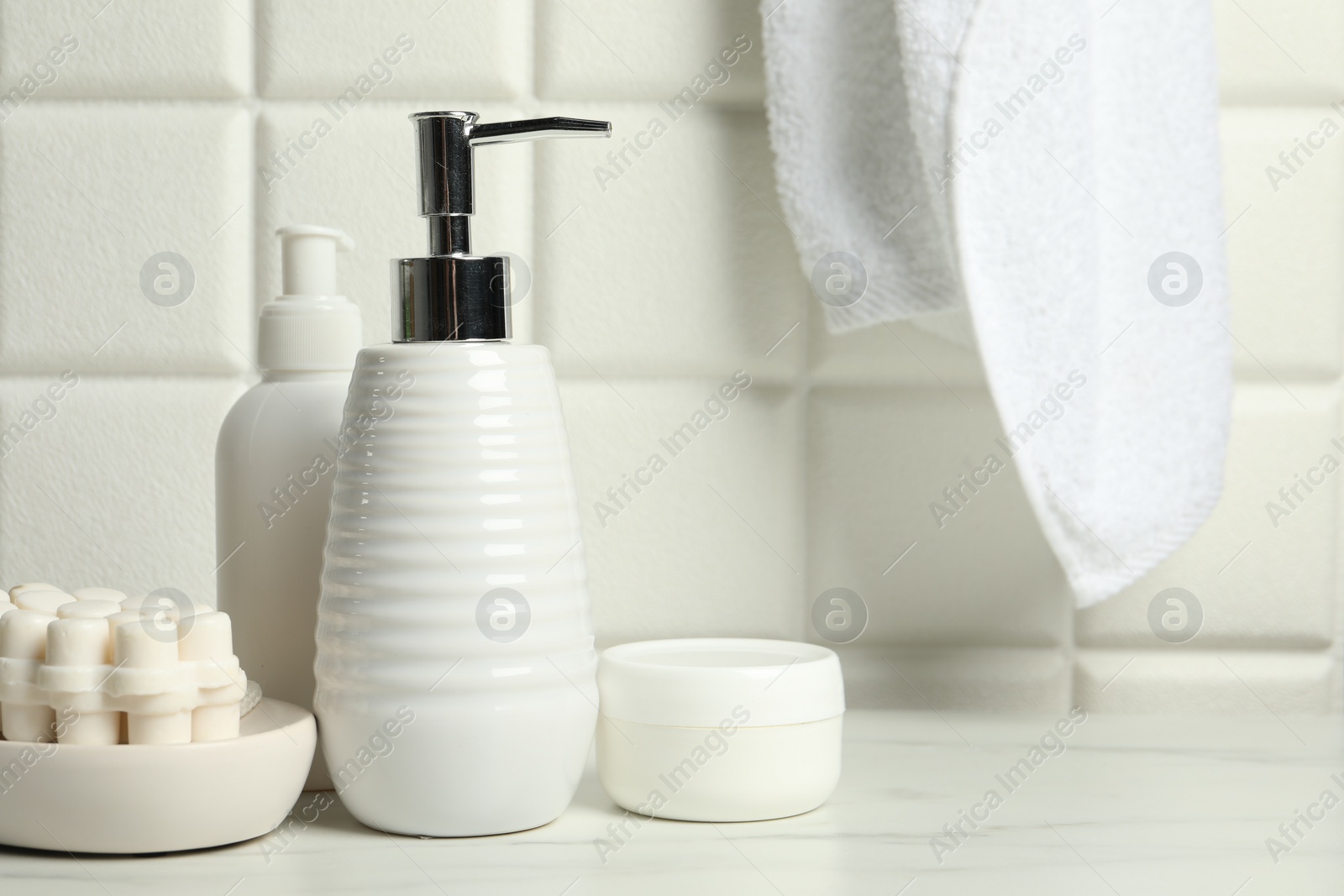 Photo of Different bath accessories and personal care products on white table near tiled wall