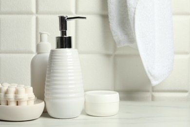 Photo of Different bath accessories and personal care products on white table near tiled wall