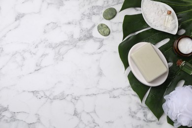 Flat lay composition with different spa products and tropical leaf on white marble table. Space for text