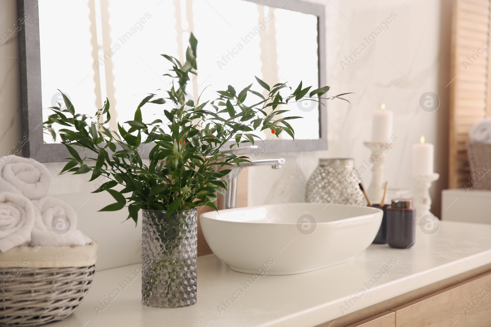 Photo of Vase with beautiful branches and fresh towels near vessel sink in bathroom. Interior design