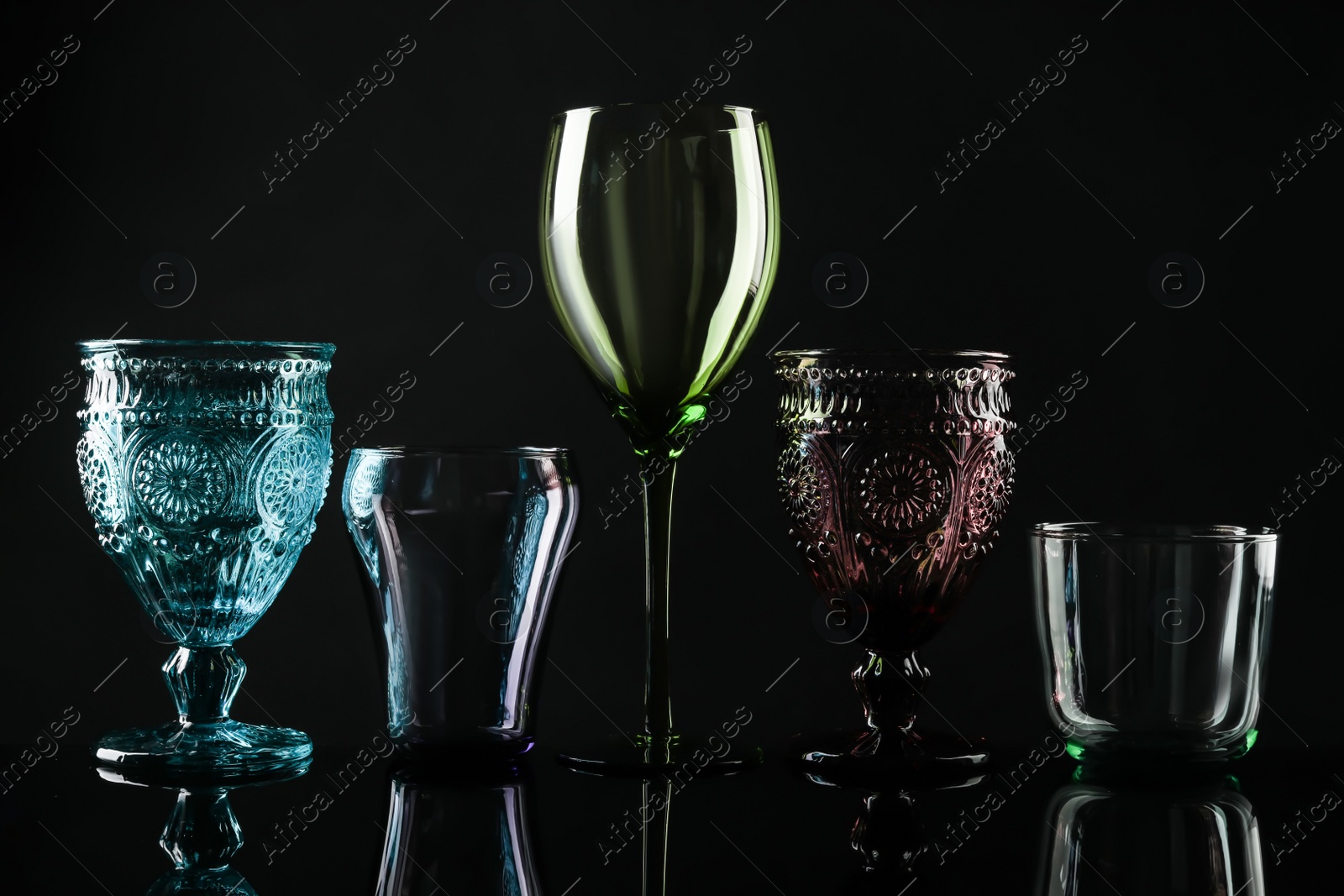 Photo of Set of different colorful empty glasses on black background