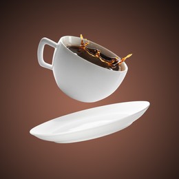 Image of White cup of coffee levitating on brown background