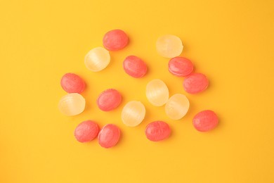 Photo of Many different colorful cough drops on orange background, flat lay