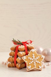 Photo of Tasty Christmas cookies tied with red ribbon and festive decor on beige wooden table, space for text