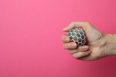 Photo of Woman holding colorful slime on pink background, closeup. Antistress toy