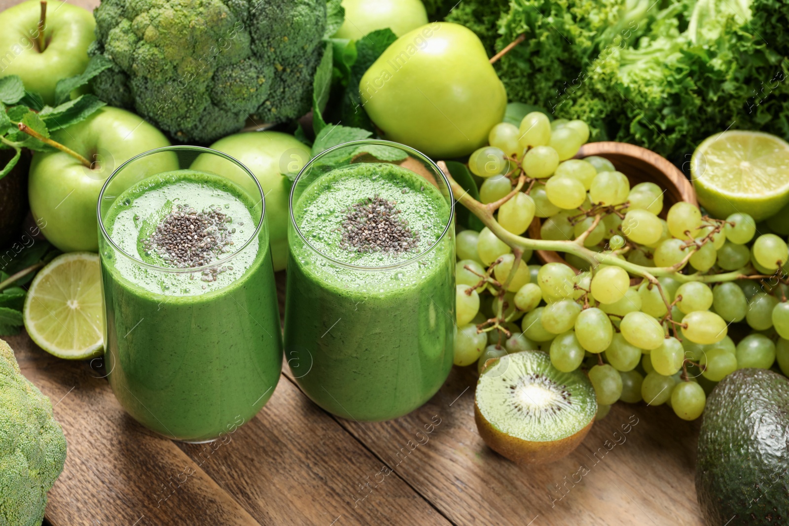 Photo of Glasses of fresh green smoothie and ingredients on wooden table