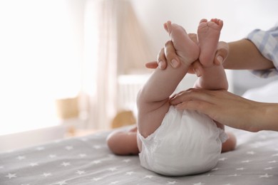 Mother changing her baby's diaper on bed