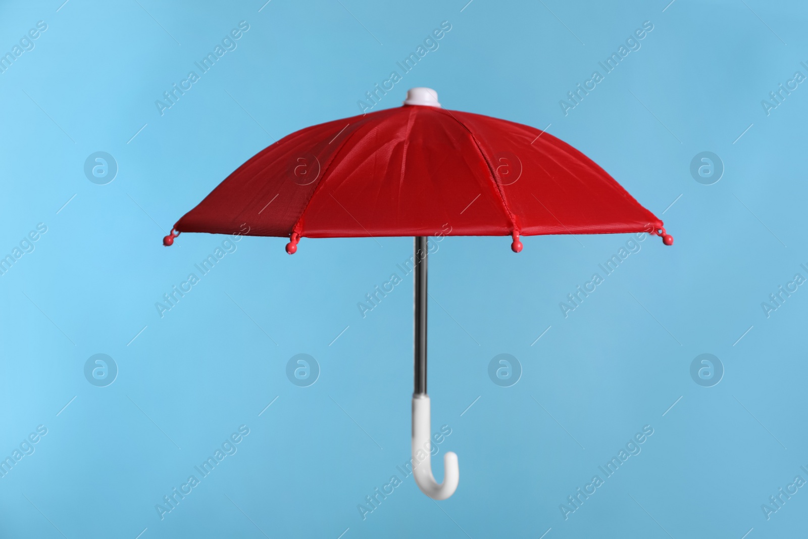 Photo of Open small red umbrella on light blue background