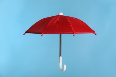 Photo of Open small red umbrella on light blue background