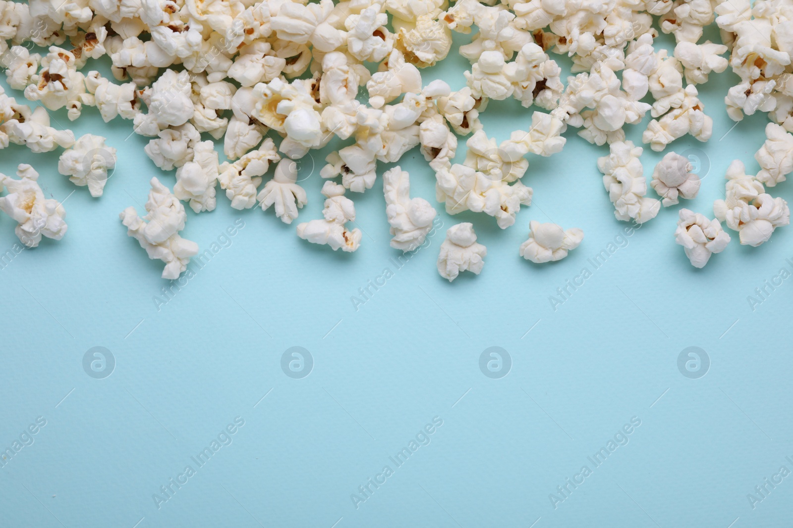 Photo of Tasty popcorn on light blue background, flat lay. Space for text