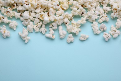 Tasty popcorn on light blue background, flat lay. Space for text