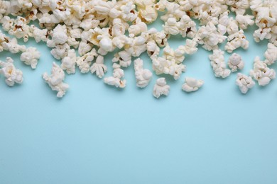 Photo of Tasty popcorn on light blue background, flat lay. Space for text