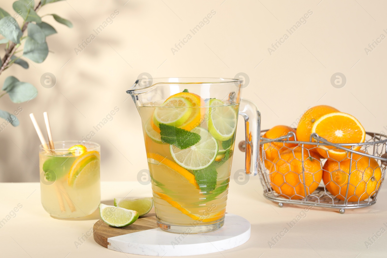 Photo of Freshly made lemonade with mint in jug and glass on beige background