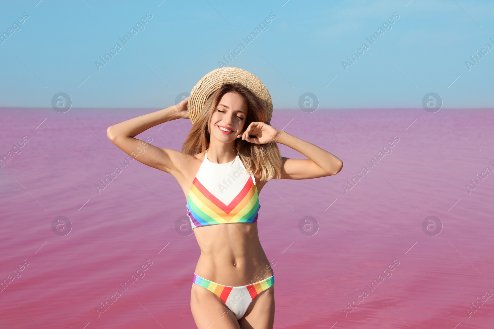 Photo of Beautiful woman in swimsuit posing near pink lake on sunny day