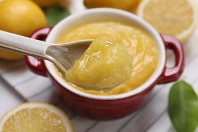 Photo of Taking delicious lemon curd from bowl at table, closeup