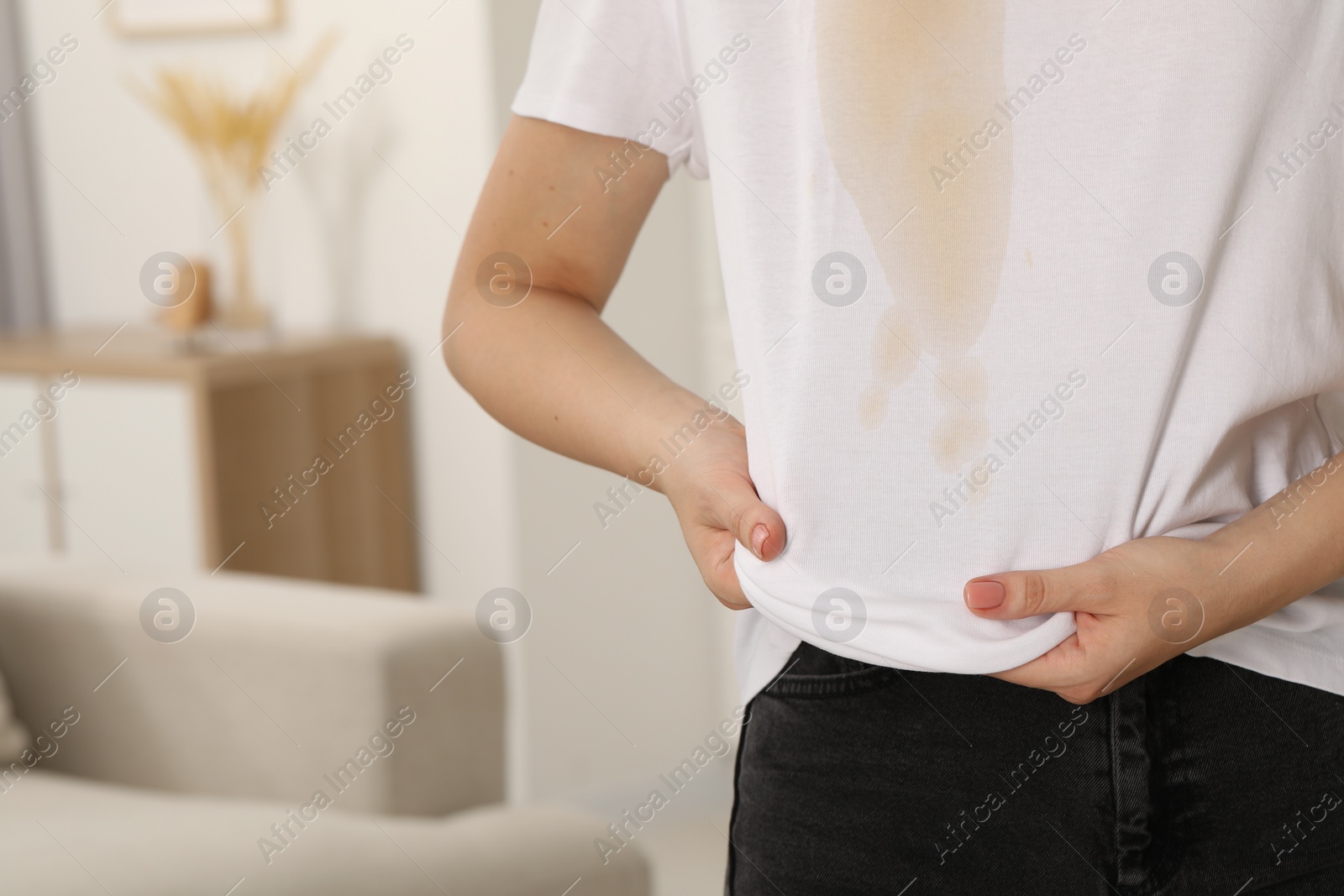 Photo of Woman showing stain from coffee on her shirt indoors, closeup. Space for text