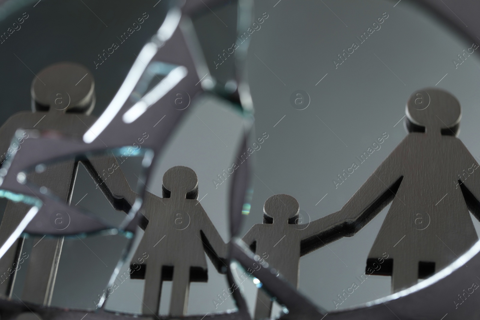Photo of Human figures reflected in broken mirror on gray background, closeup. Divorce concept
