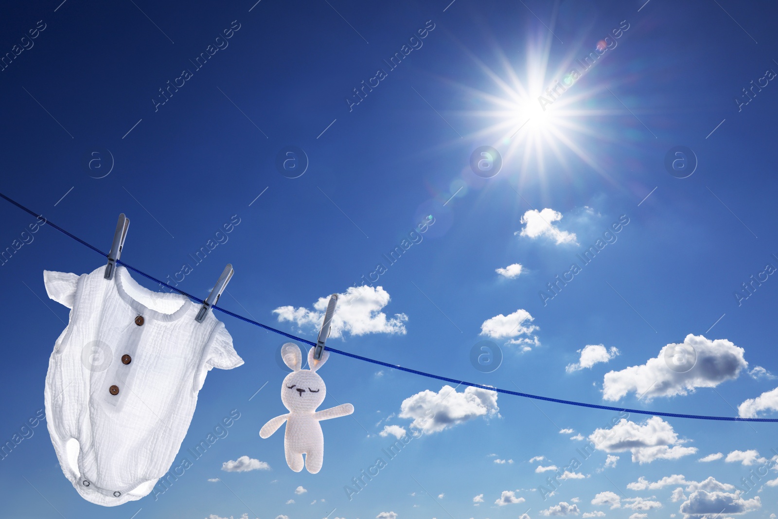 Image of Baby onesie and crochet toy drying on washing line against sky