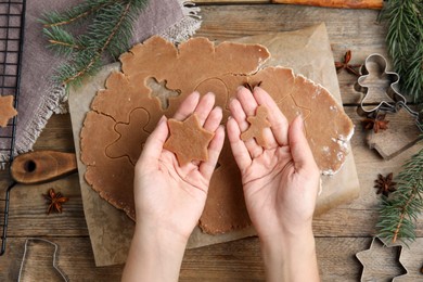 Photo of Woman making gingerbread Christmas cookies at wooden table, top view